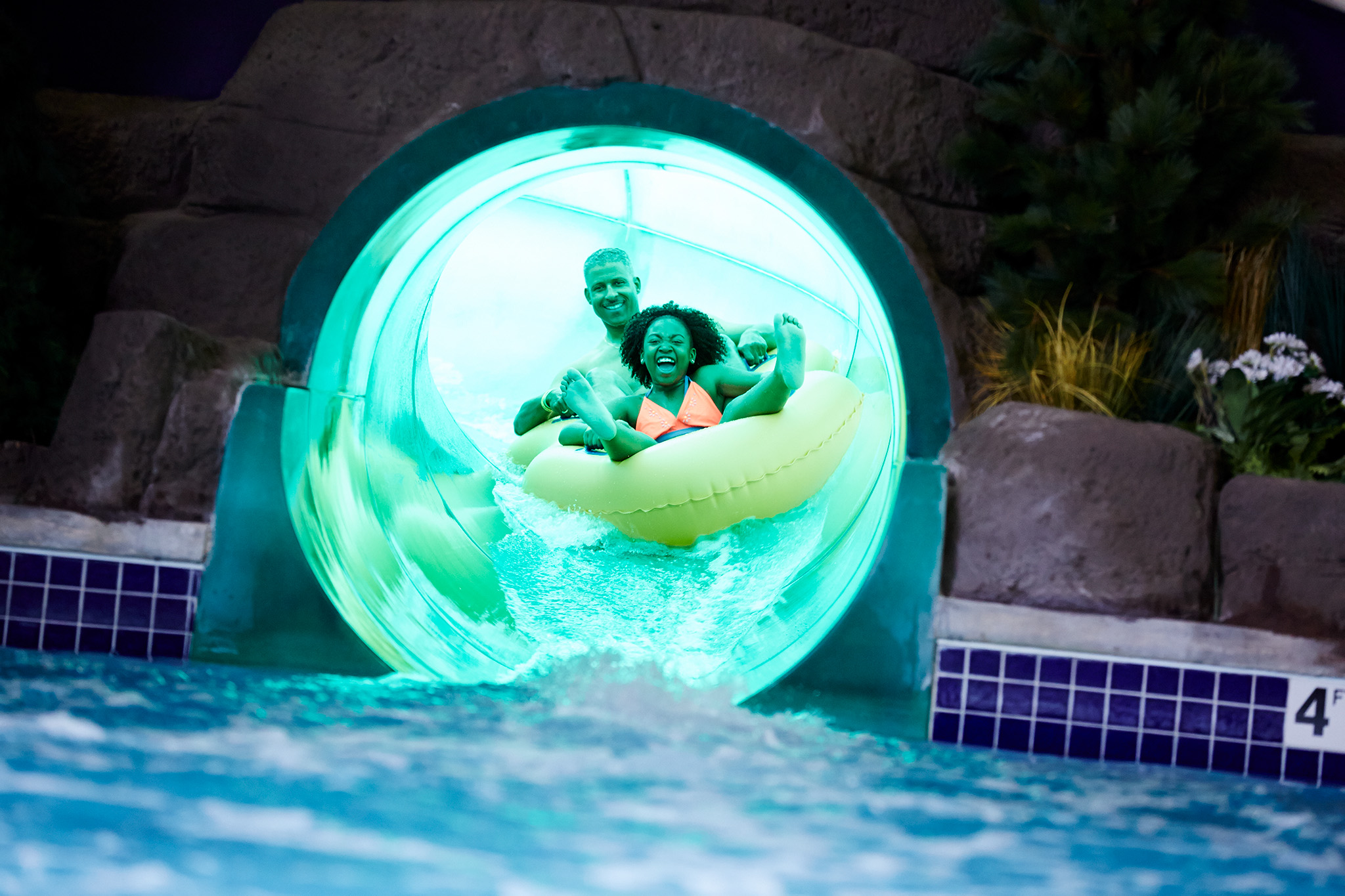 girl and father on a tub at the bottom of a water slide