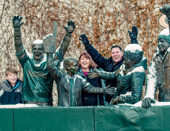 family posing around packers fan statues
